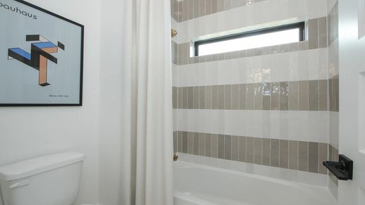 Elegant striped tiles and sleek fixtures enhance this Coastal Point bathroom's modern allure.