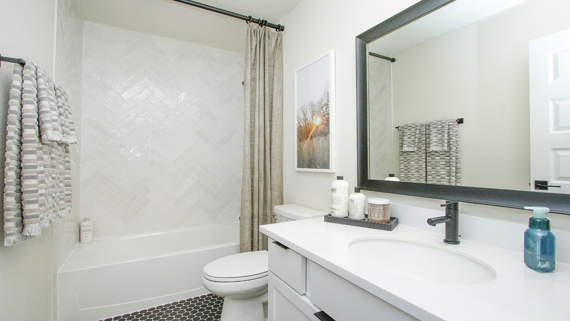 Featuring exquisite herringbone tile and sleek fixtures, this bathroom epitomizes luxury at Colony at Pinehurst.