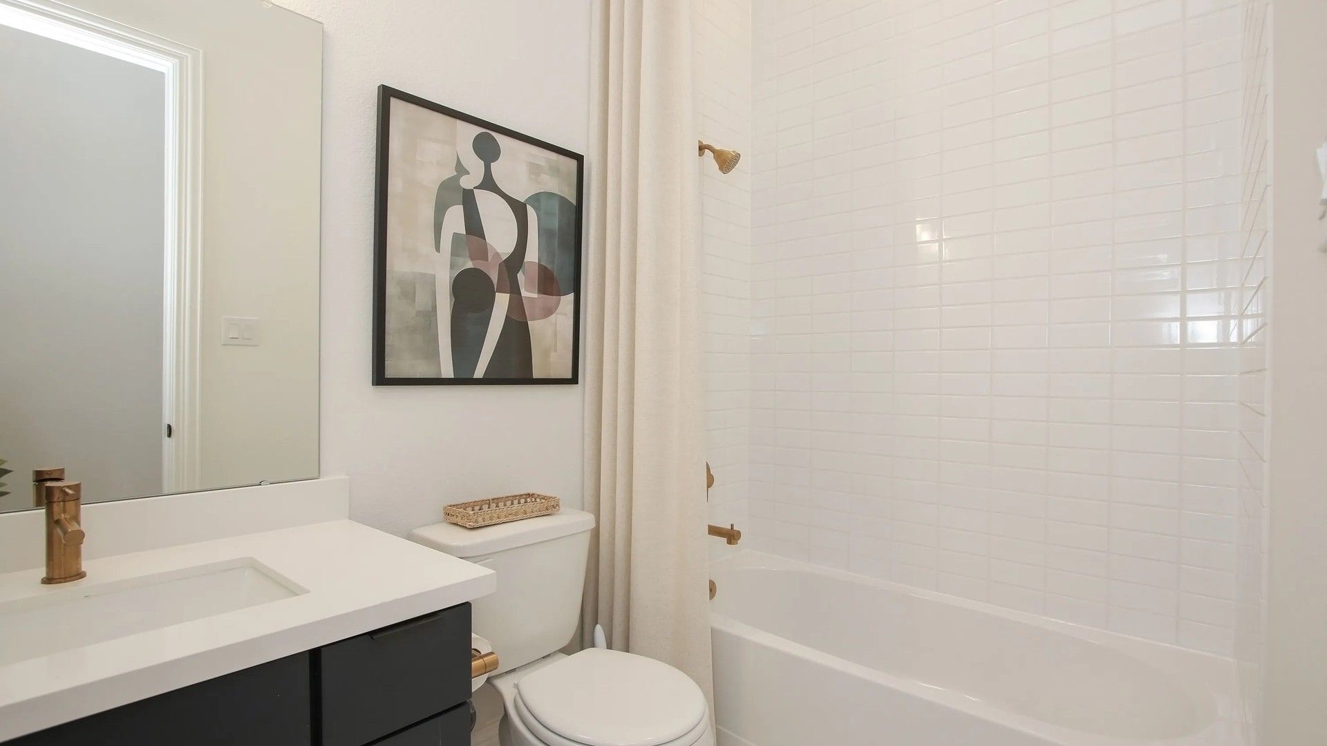 Sophisticated white tiling and brass fixtures in a luxurious Coastal Point bathroom reflect modern elegance.