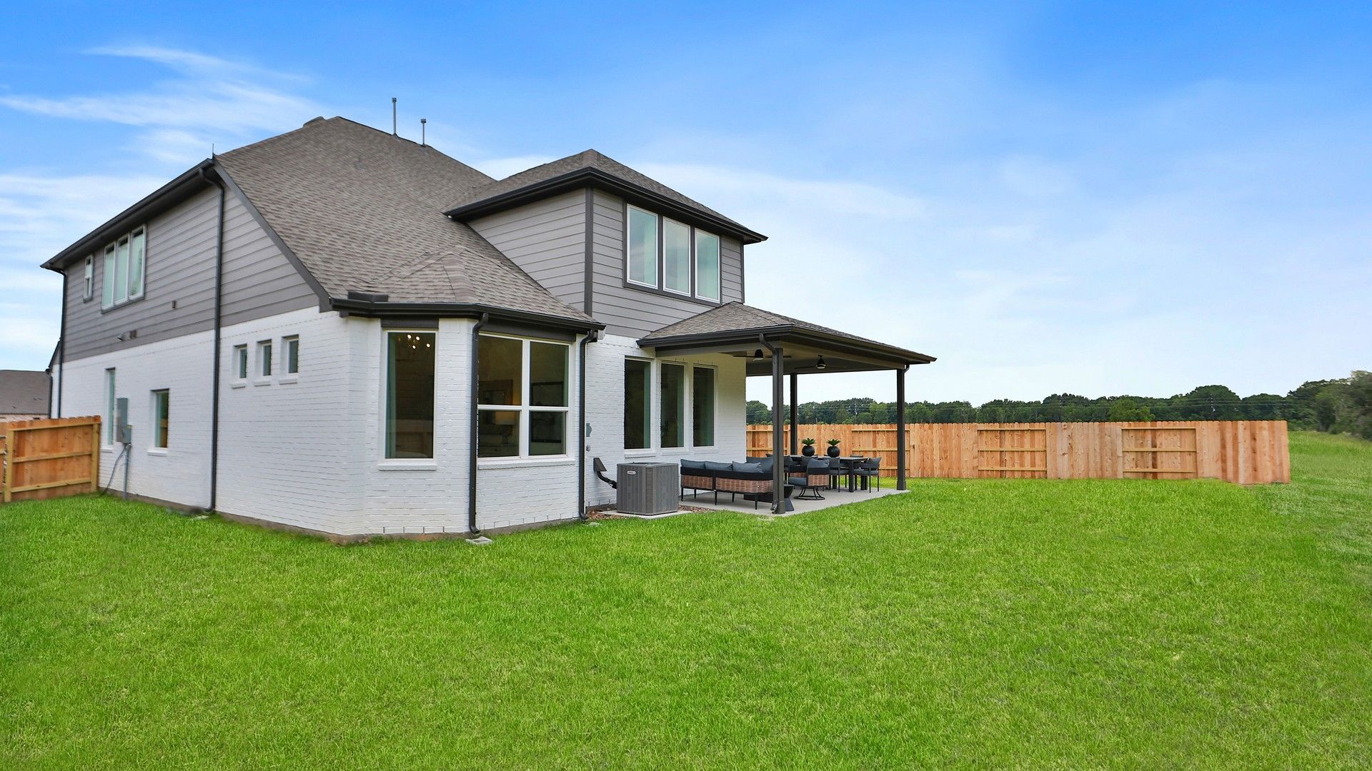 Elegant Katy Lakes residence featuring a spacious covered patio and expansive, manicured lawn.