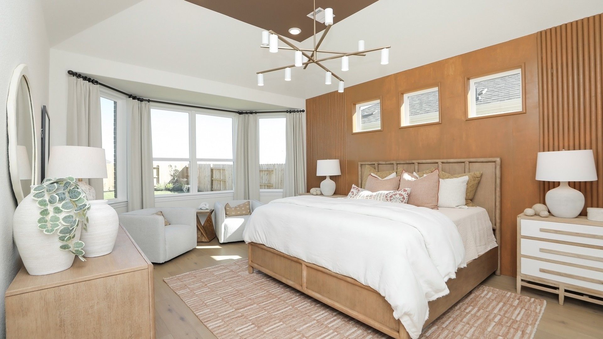 Luxurious bedroom with wood paneling, designer chandelier, and expansive windows in Brookewater community.