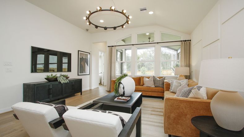 Experience luxury with vaulted ceilings and a chic chandelier, enhancing natural light in The Woodlands Hills.