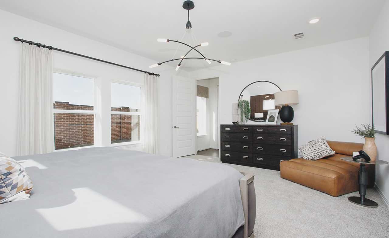 Elegant bedroom with modern lighting fixtures and plush textiles in Cypress Green community.