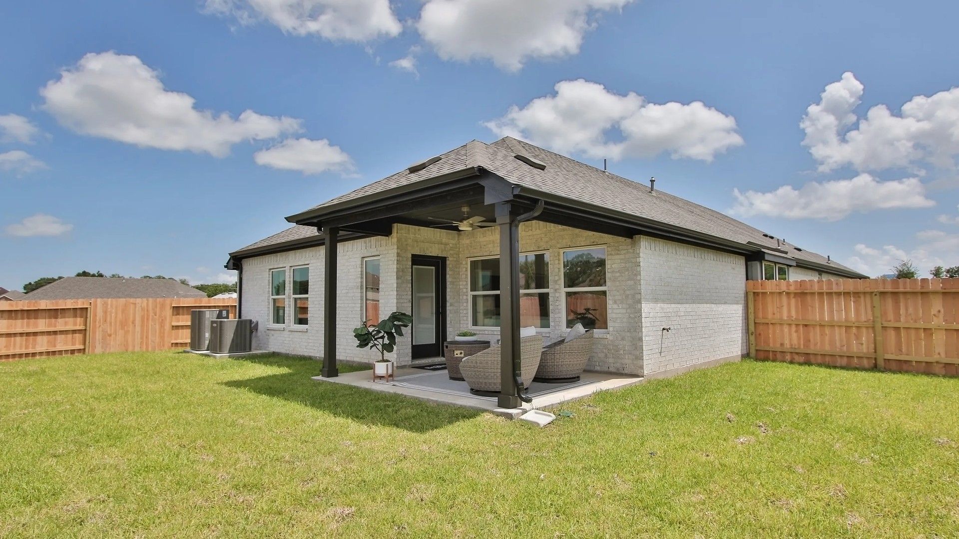 Elegant brick patio with pergola, featuring chic rattan seating. Located in Ellis Cove, showcasing refined outdoor living.