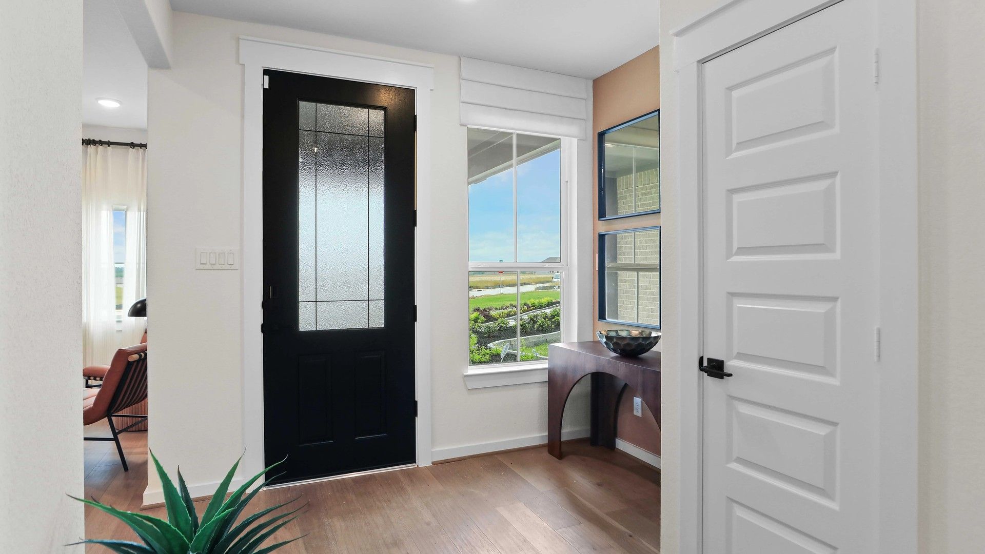Sophisticated foyer features sleek black door, wood console, and expansive window in Mostyn Springs.