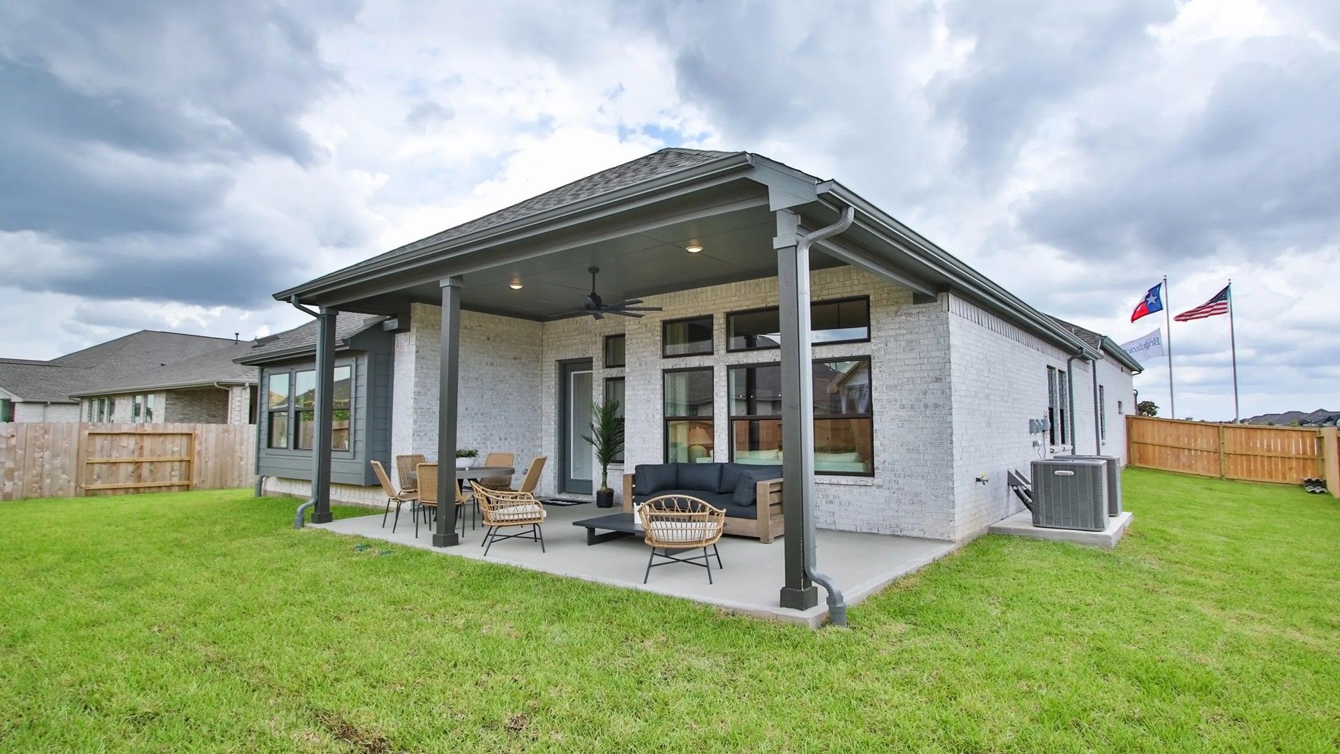 Spacious patio with ceiling fans and sleek brick exterior epitomizes luxury in Coastal Point, Texas.