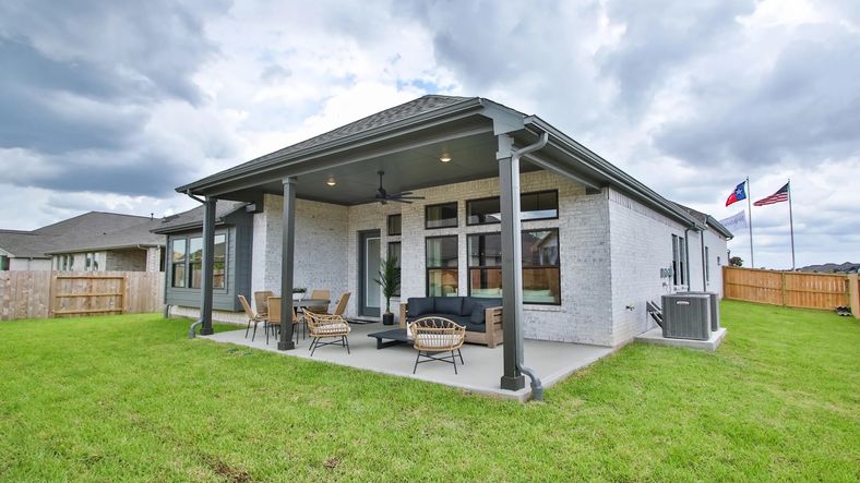 Spacious patio with ceiling fans and sleek brick exterior epitomizes luxury in Coastal Point, Texas.