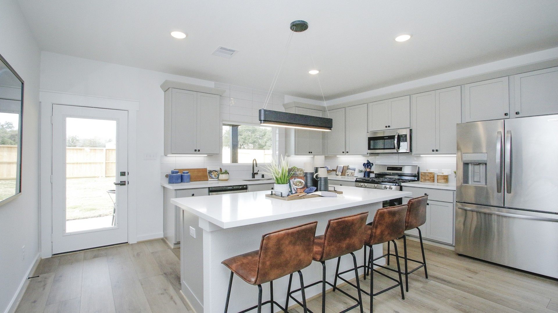 Elegant kitchen with stainless steel appliances, chic lighting, and sleek gray cabinets in Colony at Pinehurst.