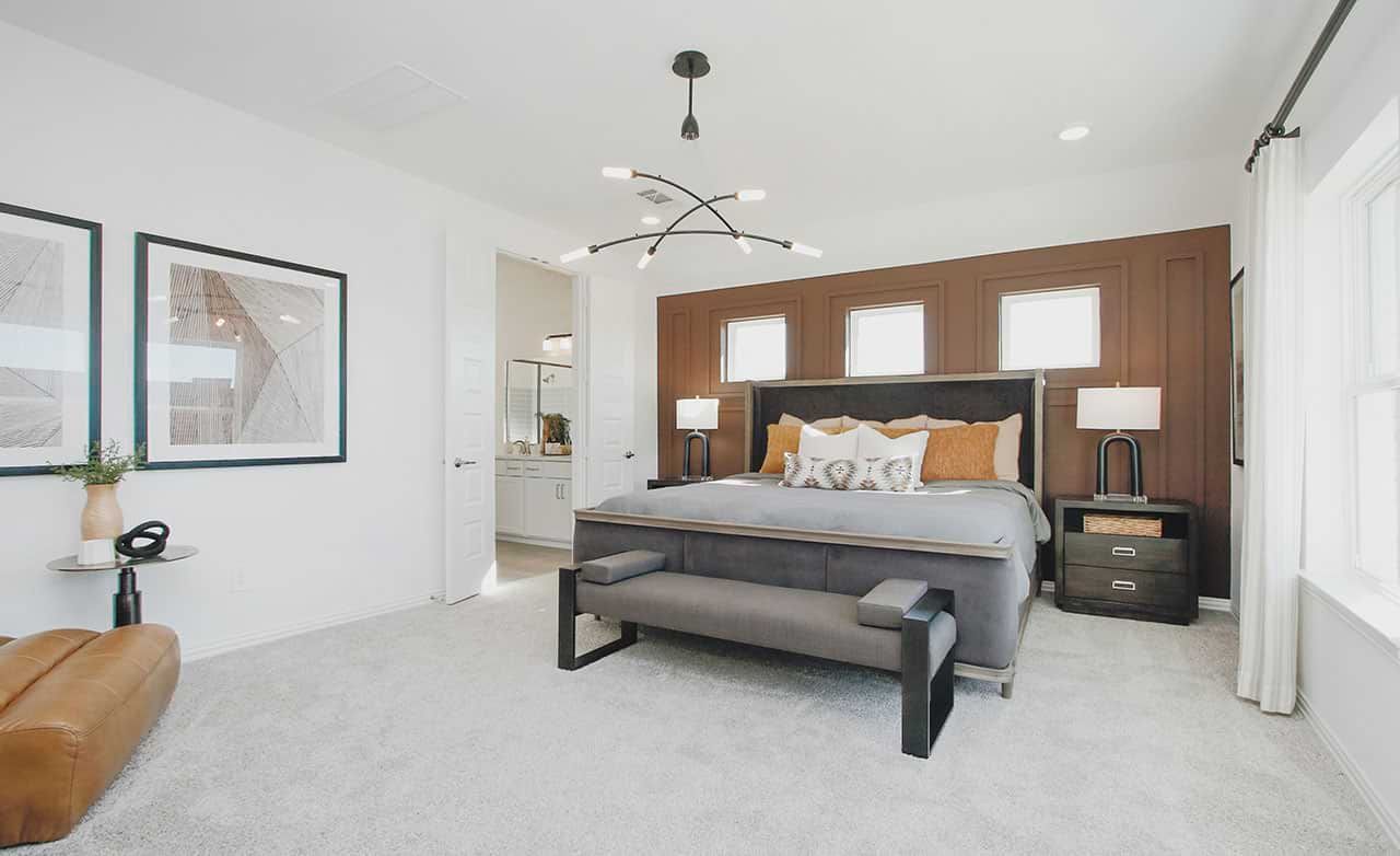 Luxurious bedroom with rich wood accent wall, stylish chandelier, plush carpet in Cypress Green.