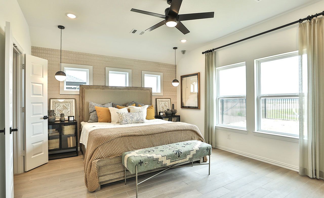 Exquisite modern bedroom with large windows, sleek ceiling fan, and plush furnishings in Bridgeland.