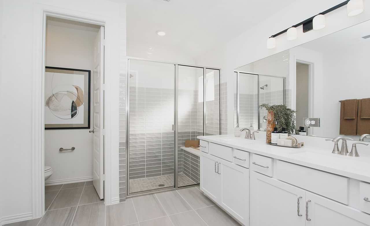 Luxurious bathroom in Cypress Green features sleek dual sinks and elegant glass shower enclosure.