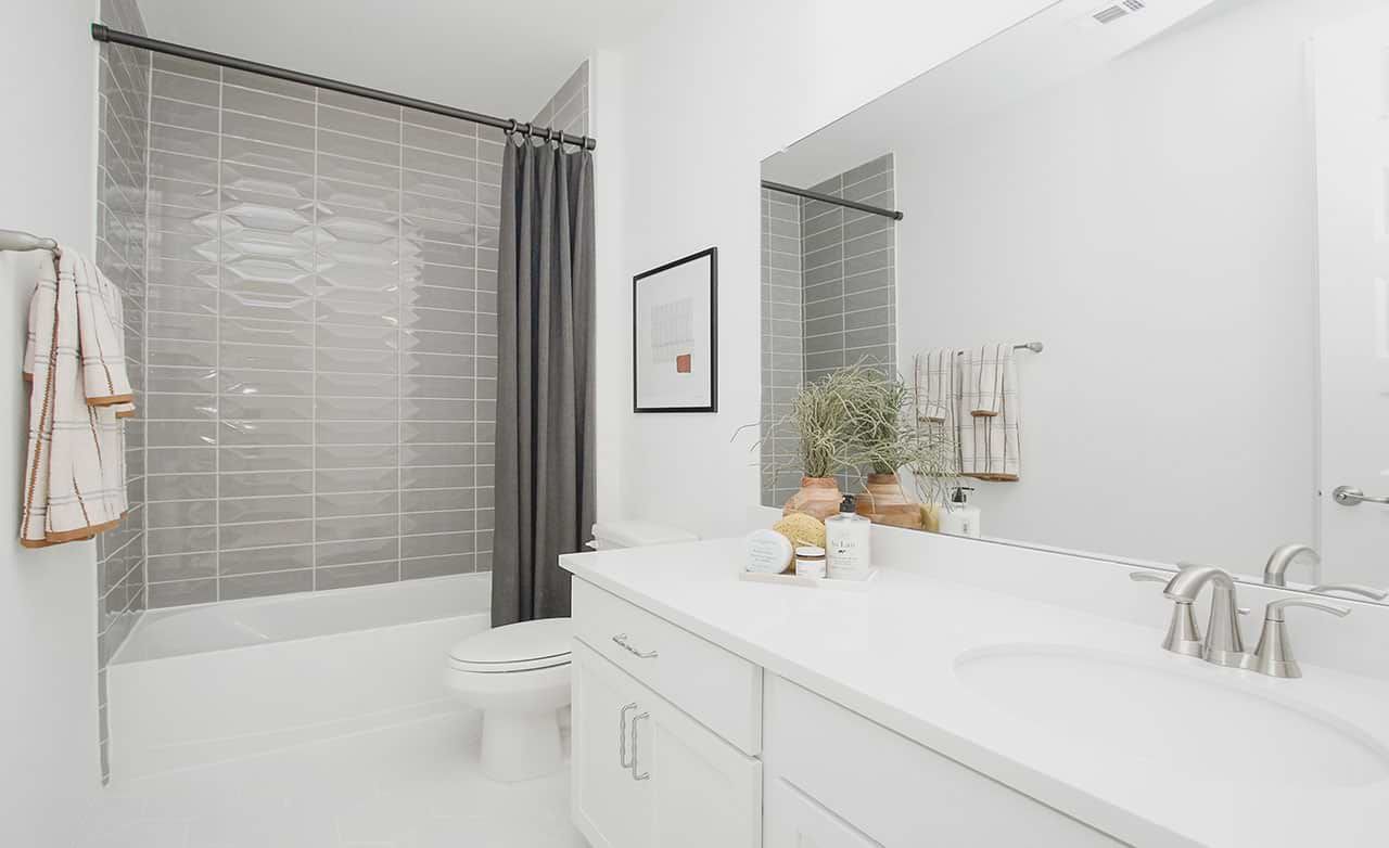 Luxurious bathroom features sleek white vanity, stylish gray tile, and premium fixtures in Cypress Green.