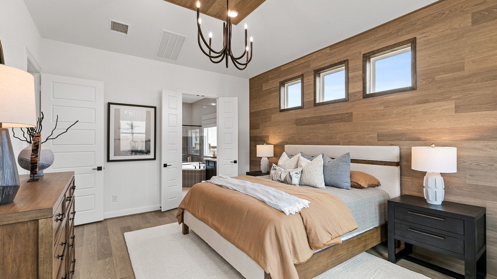 Sophisticated wood paneling and chic chandelier enrich this opulent Beamer Villas bedroom.