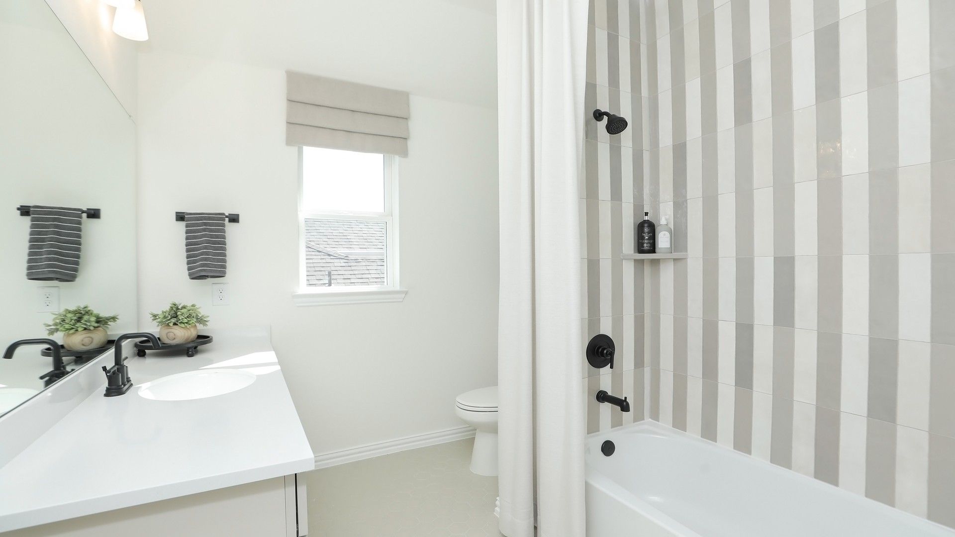 Luxurious Brookewater bathroom featuring sleek black fixtures and chic striped tiles, exuding modern elegance.