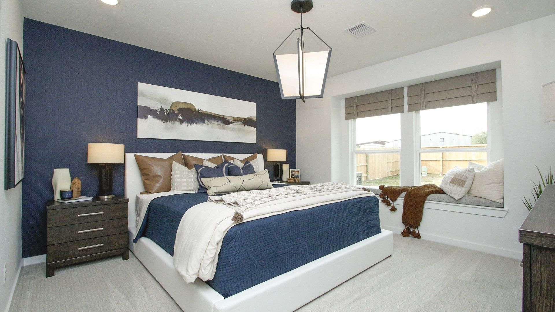 Chic bedroom features a navy accent wall, oversized windows, and designer lighting in Colony at Pinehurst.