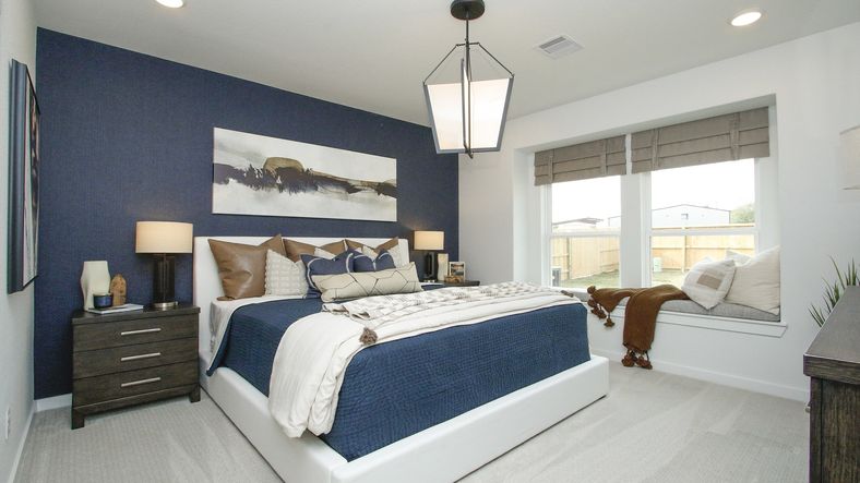 Chic bedroom features a navy accent wall, oversized windows, and designer lighting in Colony at Pinehurst.