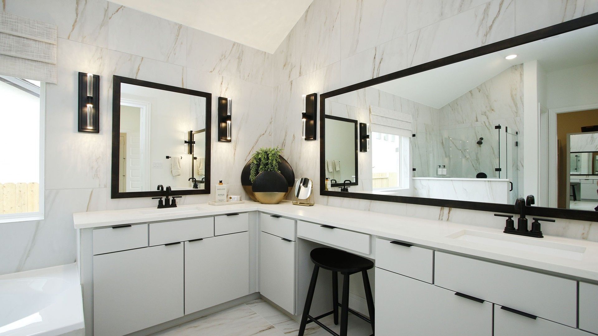 Elegant marble walls and dual vanities with striking black accents enhance this Woodlands Hills bathroom.
