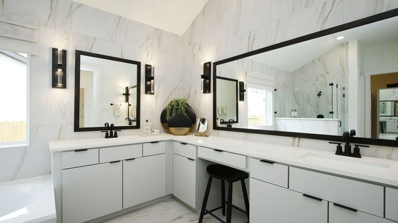 Elegant marble walls and dual vanities with striking black accents enhance this Woodlands Hills bathroom.