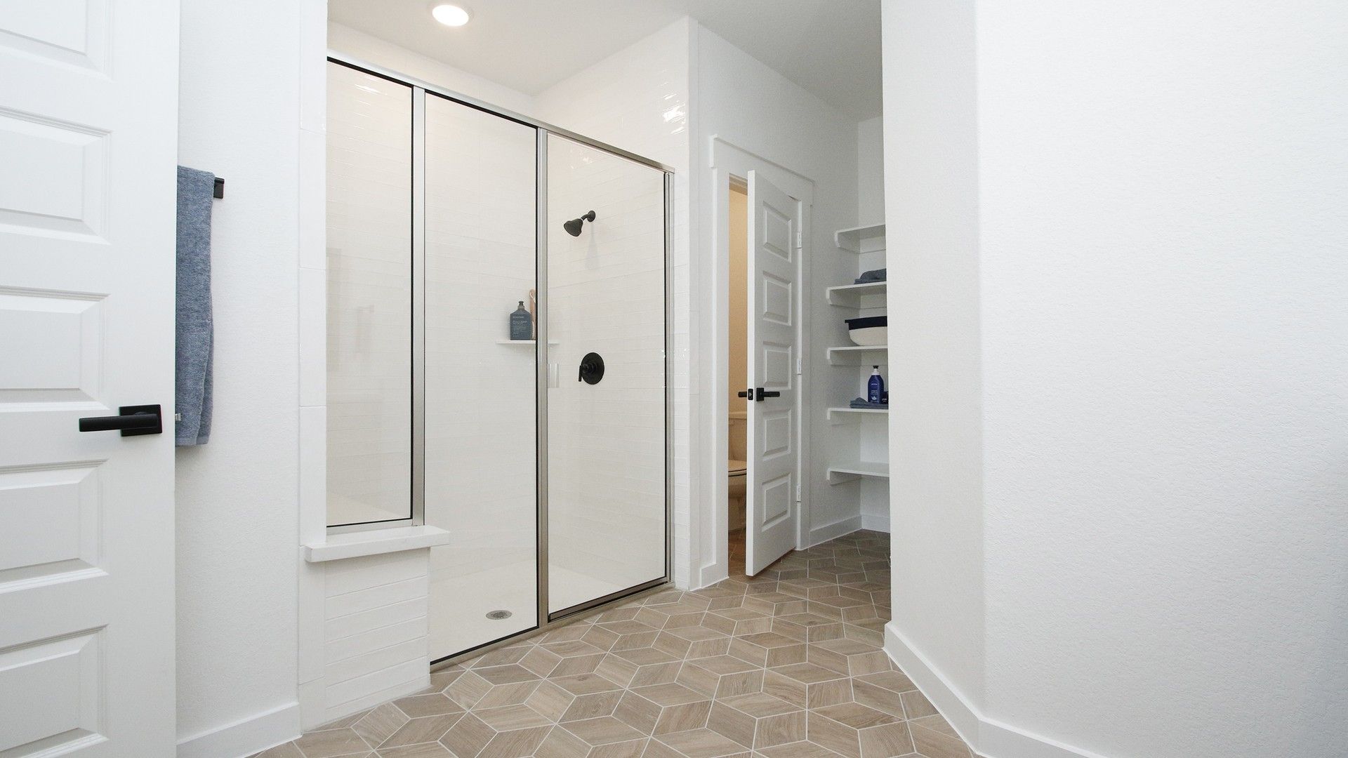 Elegant shower with sleek glass, geometric tile, and minimalist shelves in Colony at Pinehurst.