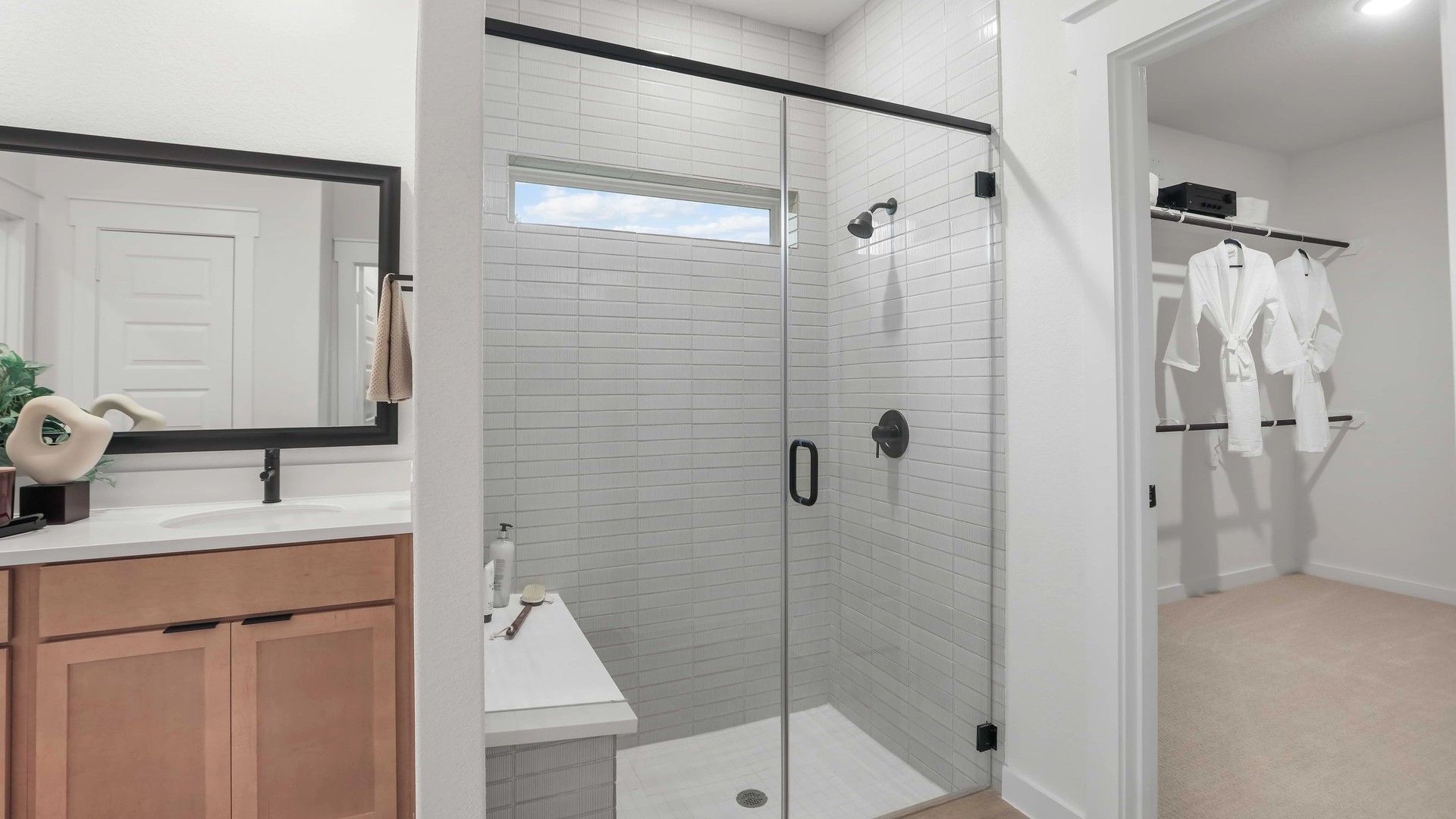Elegant glass shower, sleek wood vanity, and expansive mirror enhance this Mostyn Springs sanctuary.