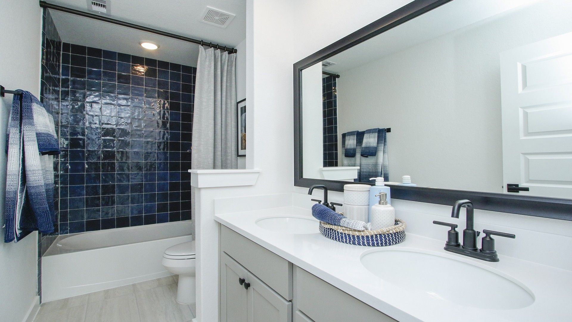 Exquisite bathroom featuring elegant navy tiles and dual sinks at Colony at Pinehurst.