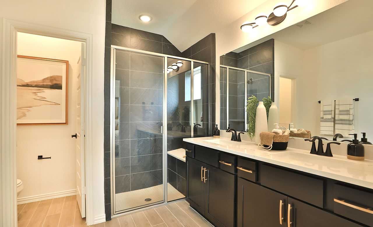 Bridgeland bath boasts exquisite glass shower, chic dark cabinetry, and refined lighting. Elegant above all.