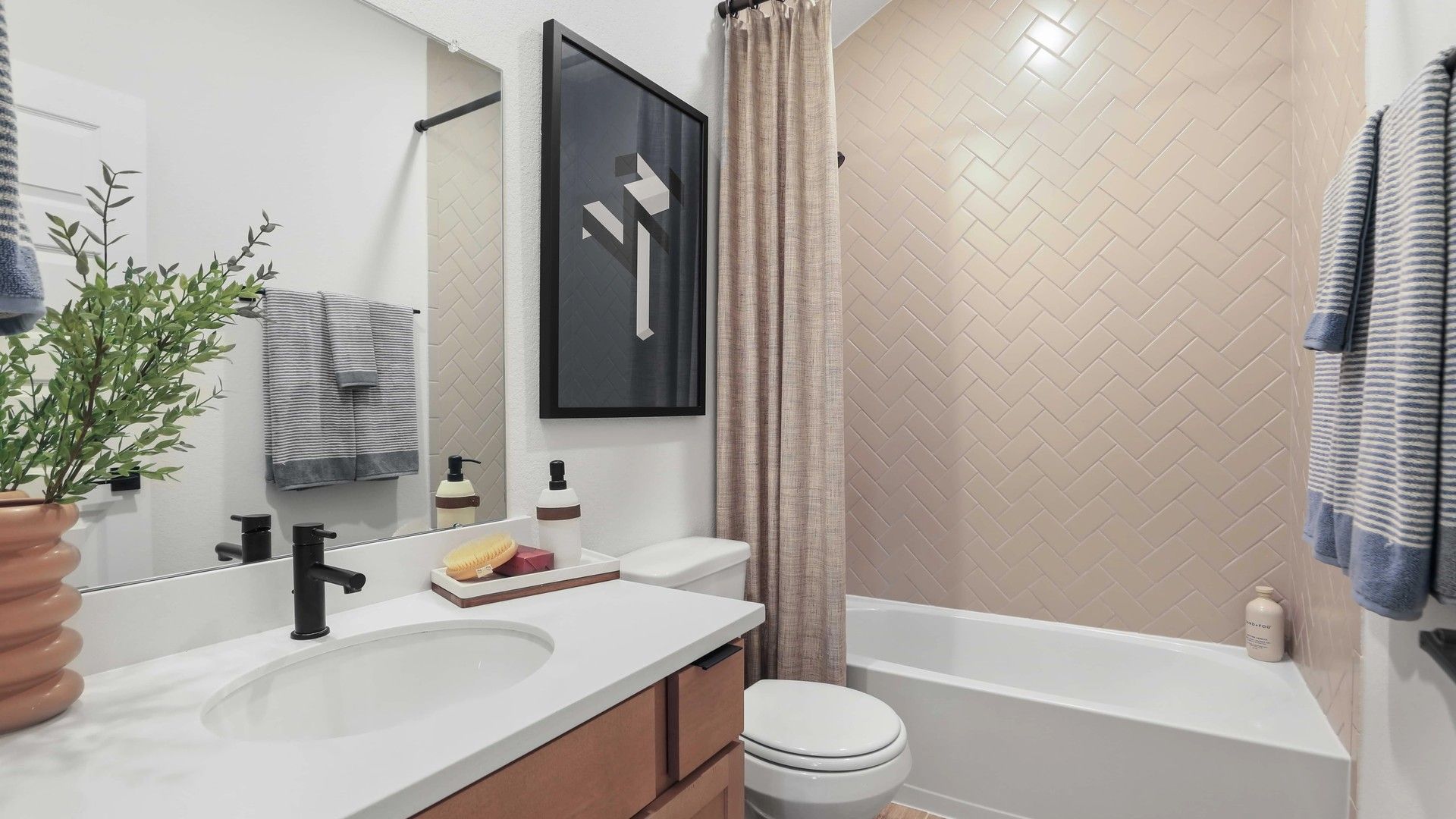 Luxurious herringbone tile and refined black fixtures elevate this Mostyn Springs bathroom design.