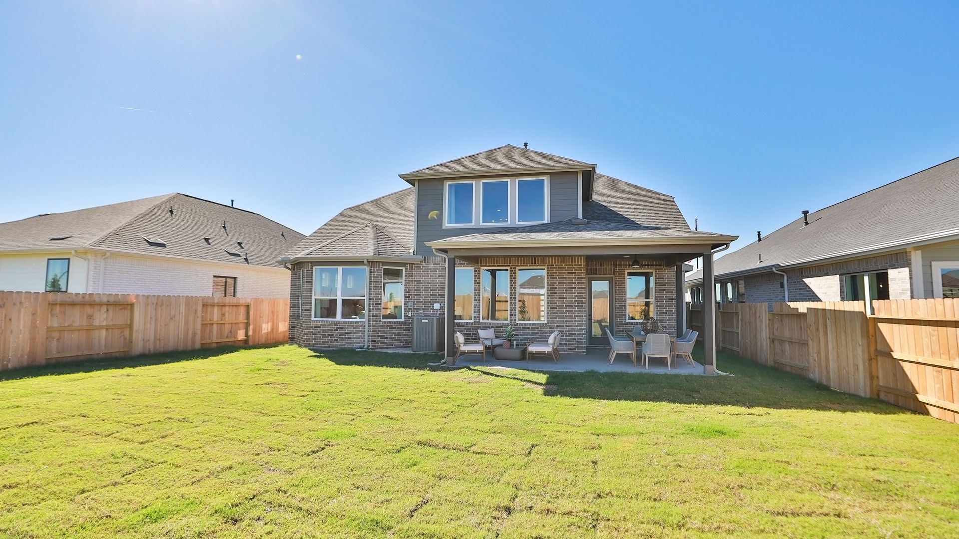 Elegant brick facade and covered patio highlight luxurious living in Brookewater community.