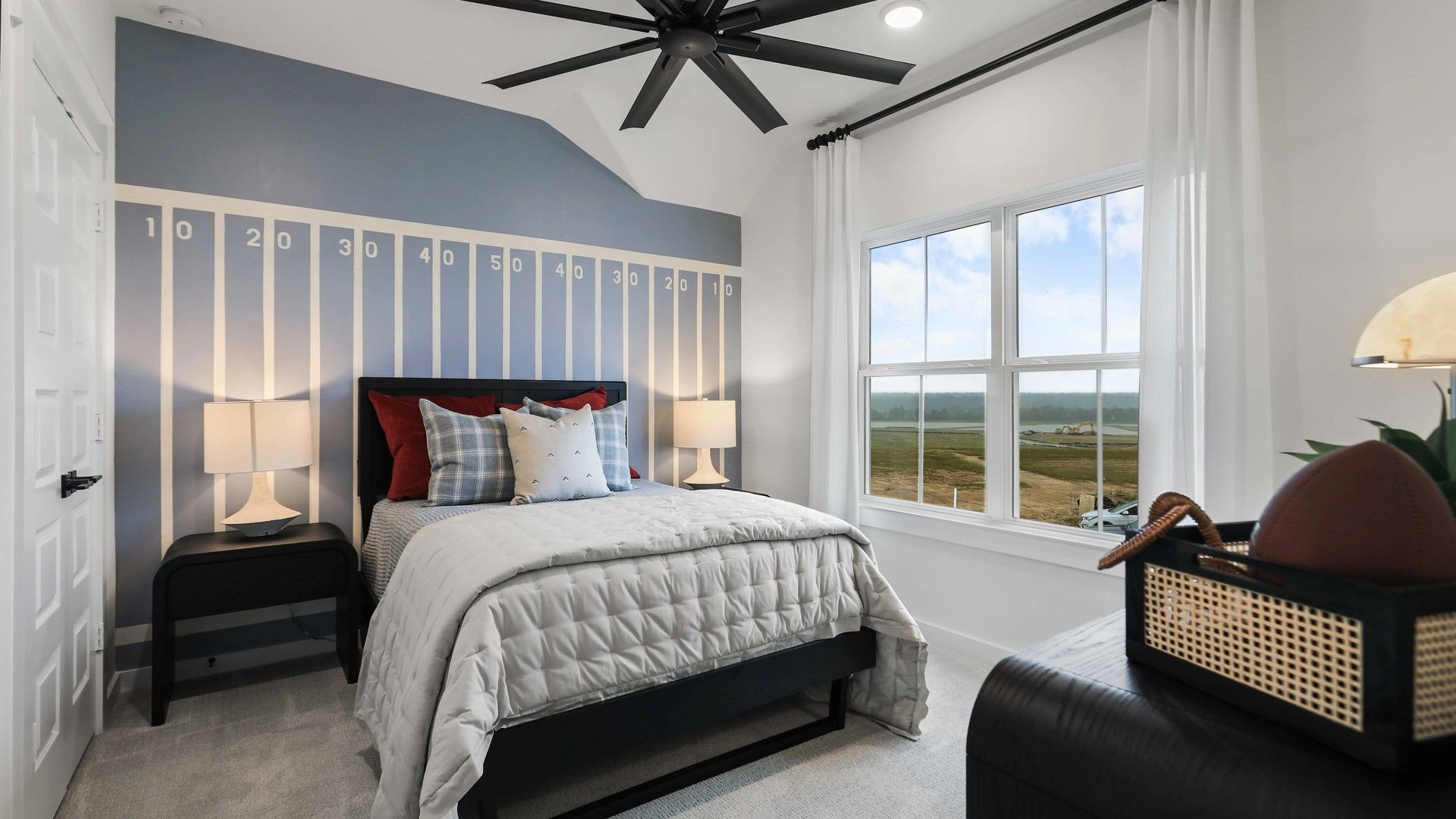 Revel in the sports-themed elegance and expansive window views in this Mostyn Springs bedroom.