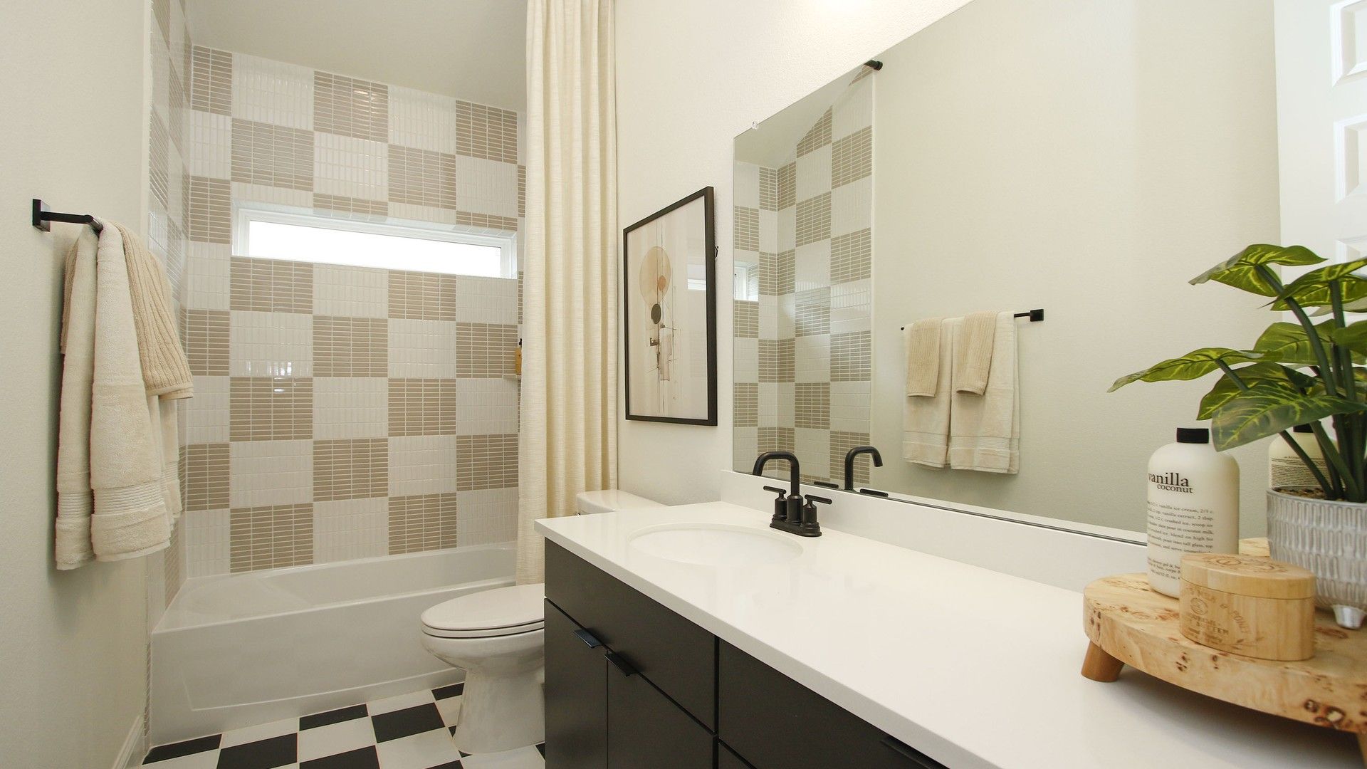 Experience sophistication in this exquisite bathroom featuring sleek checkered tiles and elegant fixtures in The Woodlands Hills.