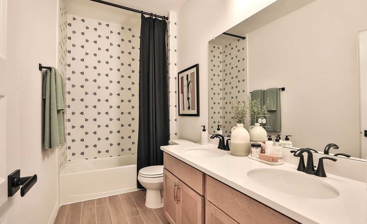 Luxurious Bridgeland bathroom features striking geometric tiles, chic black fixtures, and dual sinks.