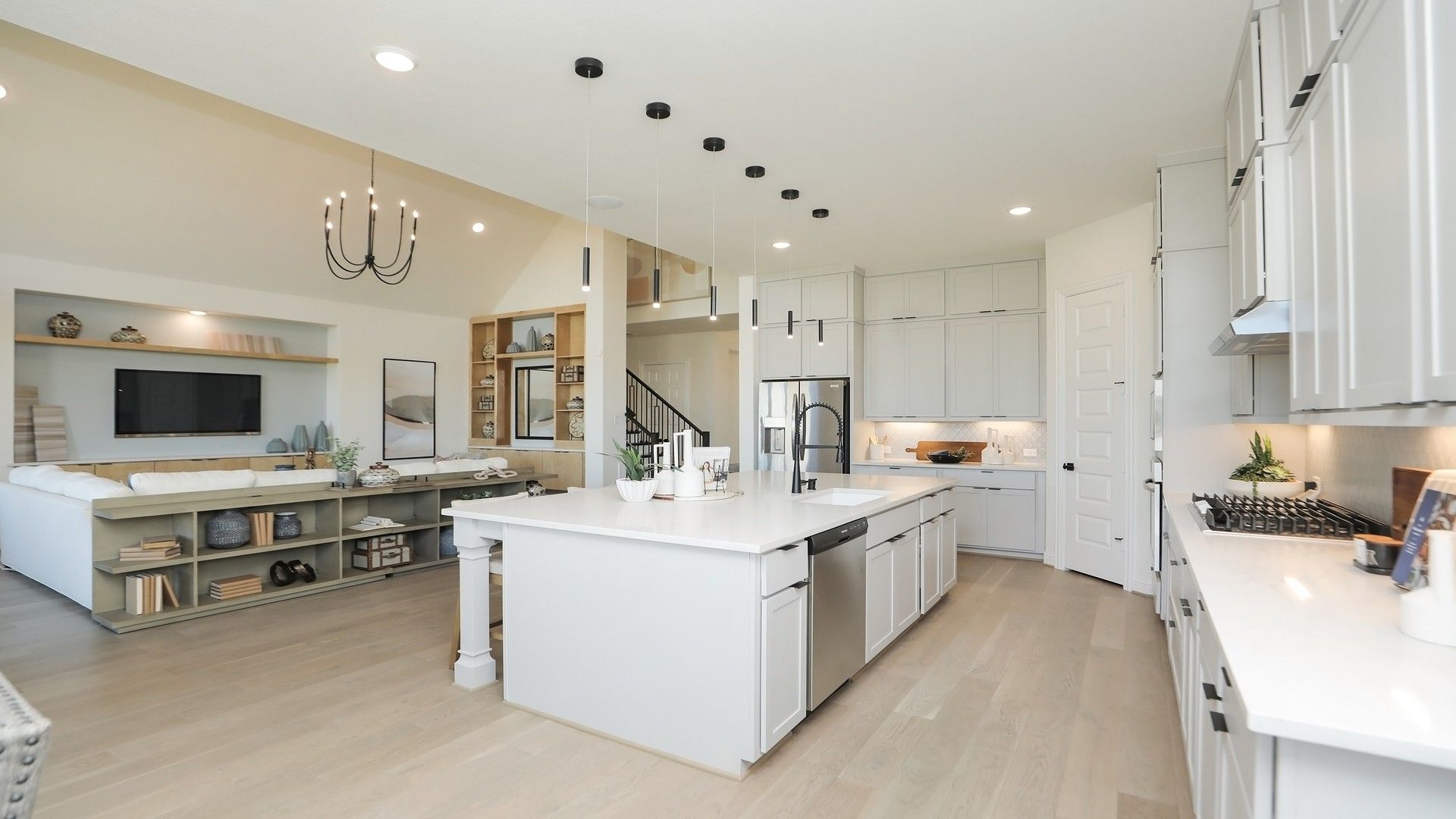 Luxurious kitchen features elegant white cabinetry, expansive island, and sleek pendant lighting in Brookewater.