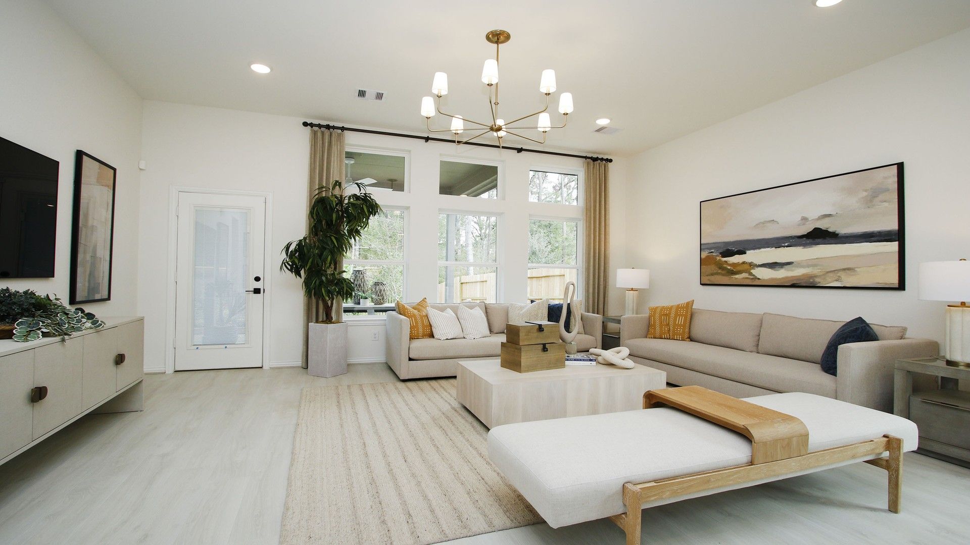 Luxurious living room boasts modern chandelier, expansive windows, and refined décor in The Woodlands Hills.