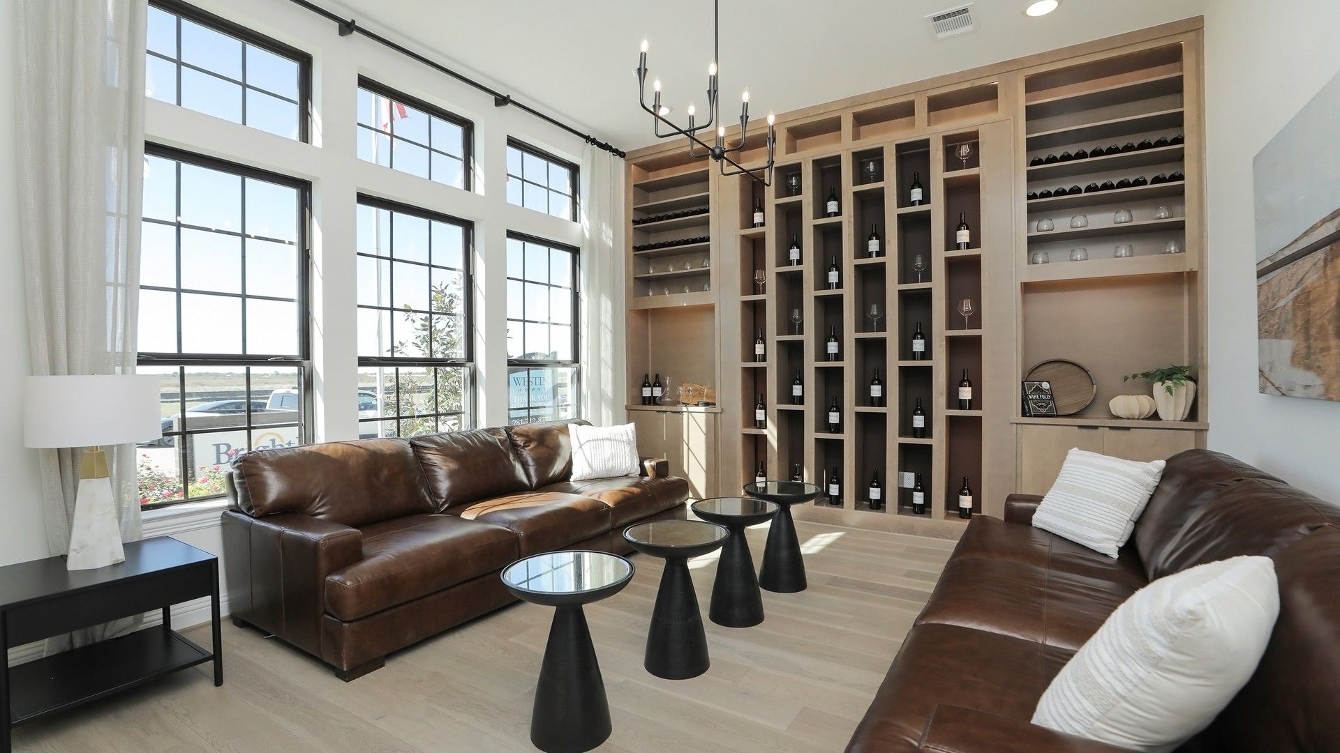 Elegant Brookewater living room features expansive windows, bespoke wine display, and refined leather furnishings.