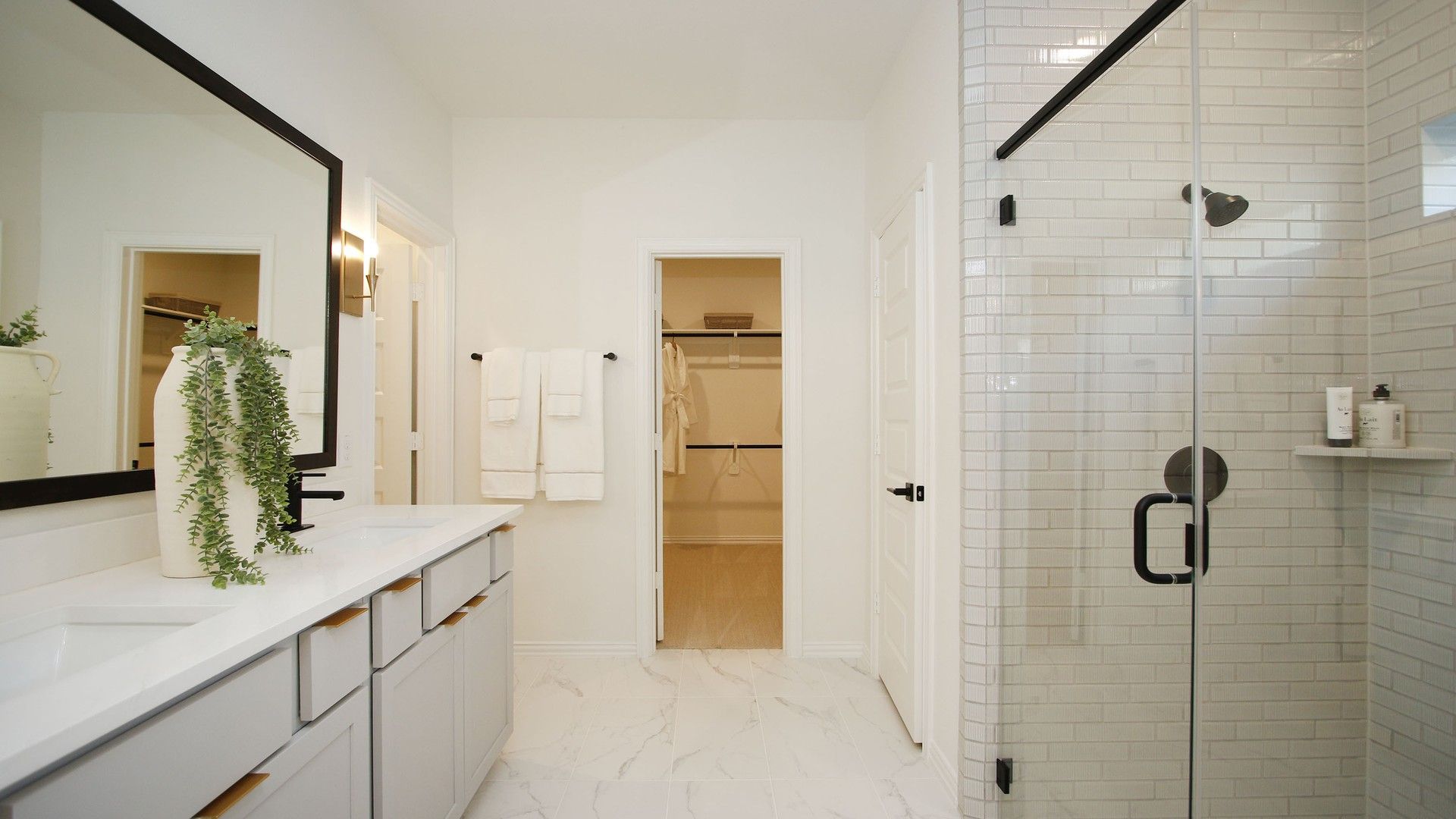 Marble tiles and frameless glass shower enhance this bathroom's elegance in The Woodlands Hills.