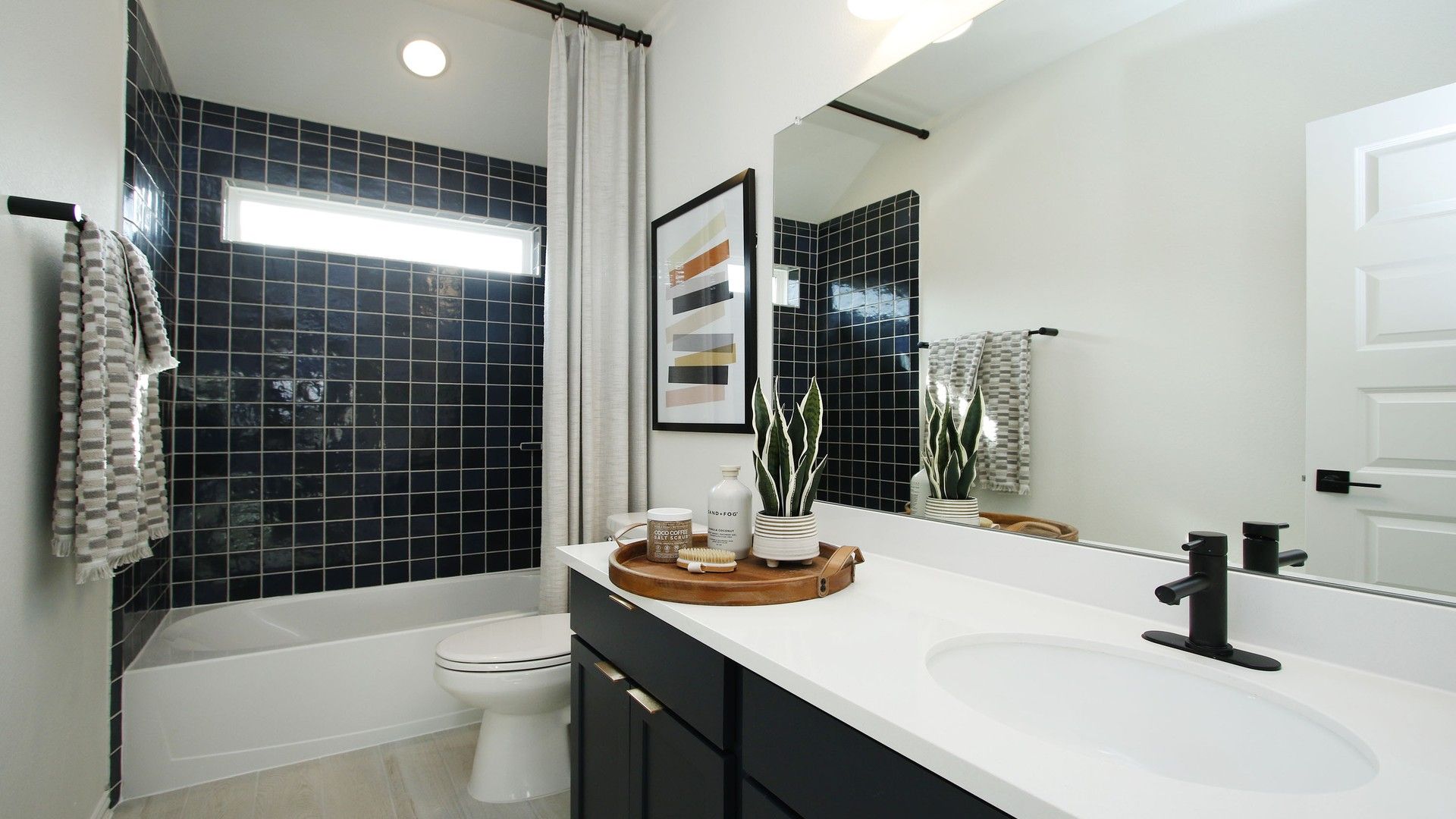 Luxurious bathroom features sleek black tiles and elegant white countertop, creating a chic in Woodlands Hills.