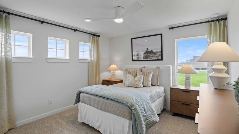 Sophisticated bedroom features plush carpet, sleek ceiling fan, and ample natural light in Mostyn Springs.