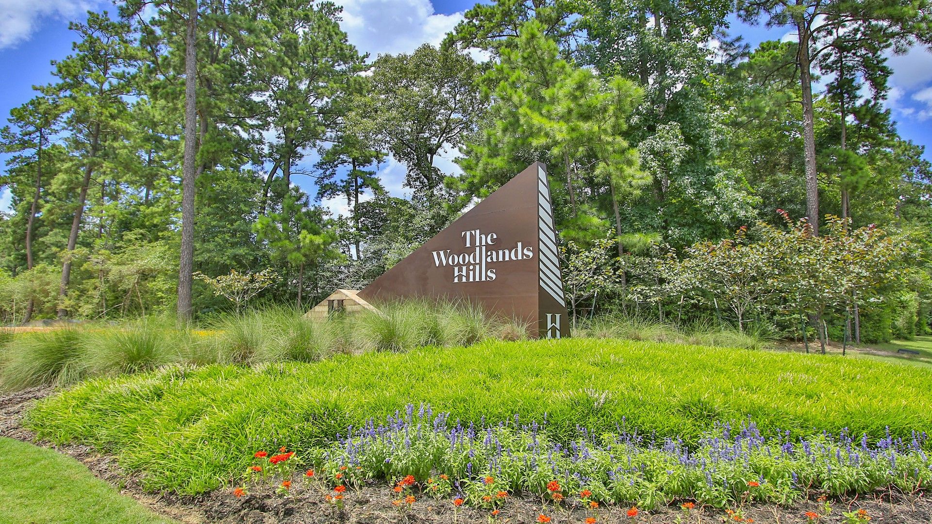 "Experience architectural elegance at The Woodlands Hills. Stunning signage complements the verdant landscape."