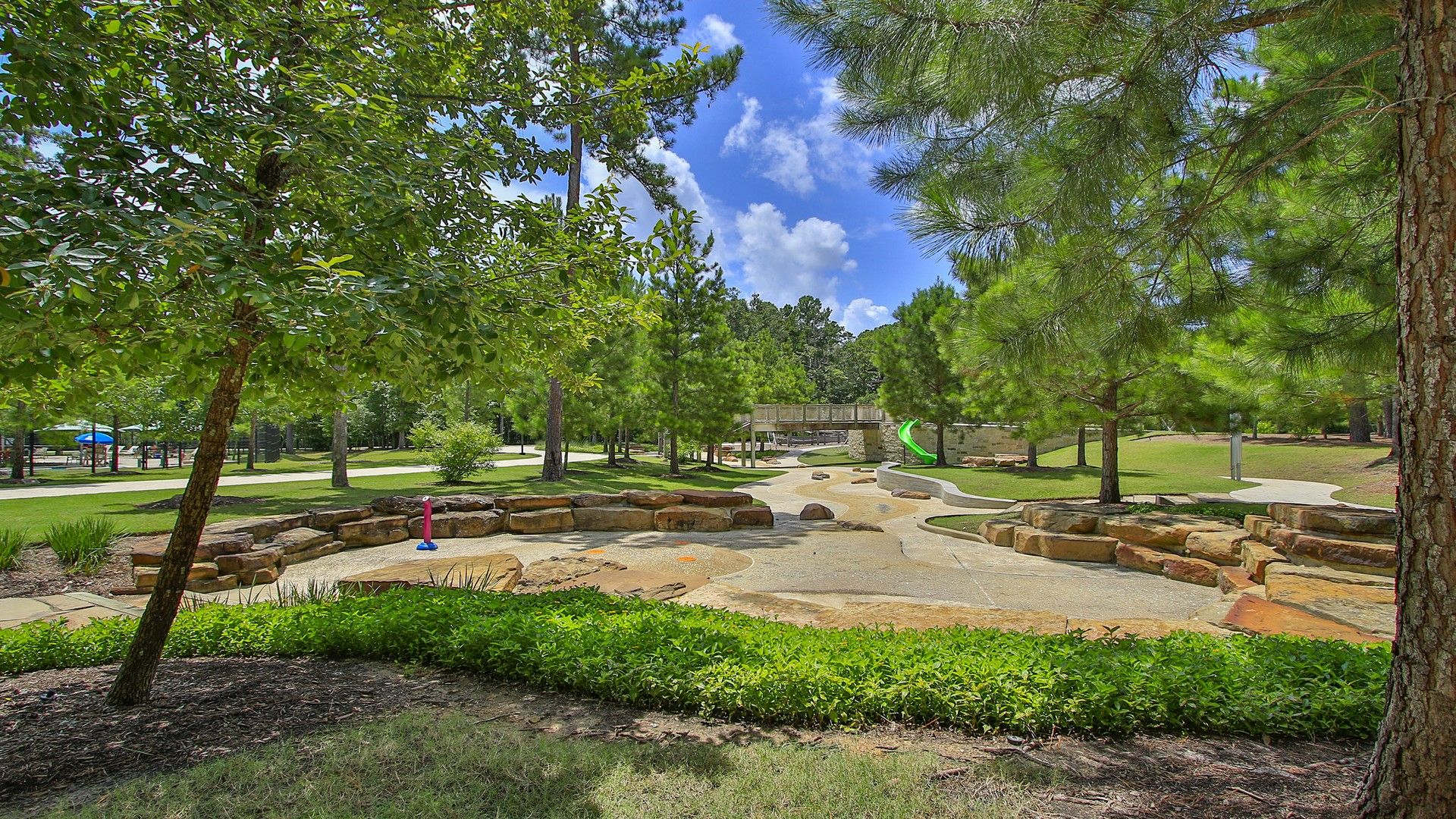 Embrace nature at The Woodlands Hills with stone pathways, lush greenery, and serene play areas.