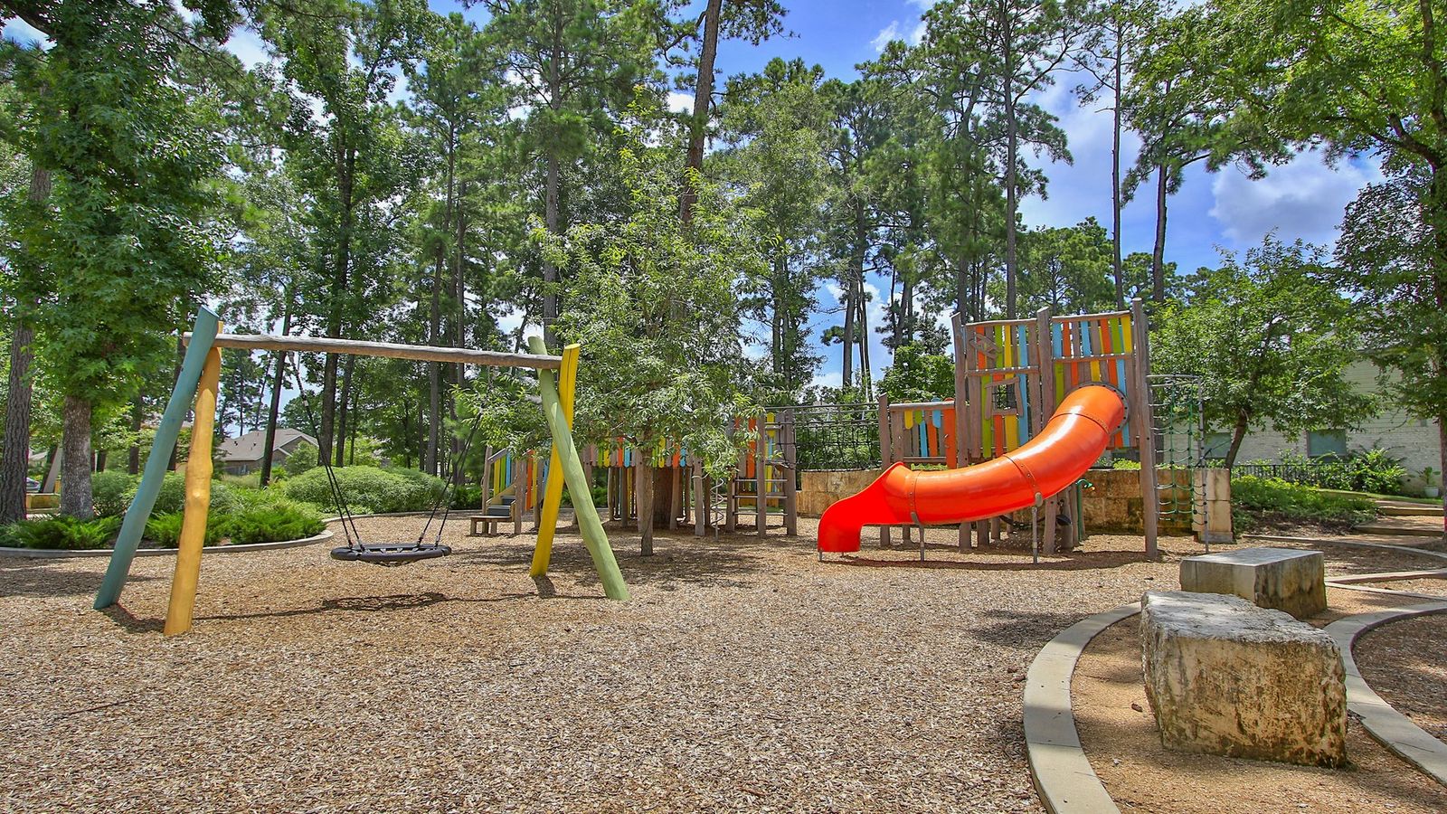 Luxurious community playground with colorful structures and organic design in The Woodlands Hills, Texas.