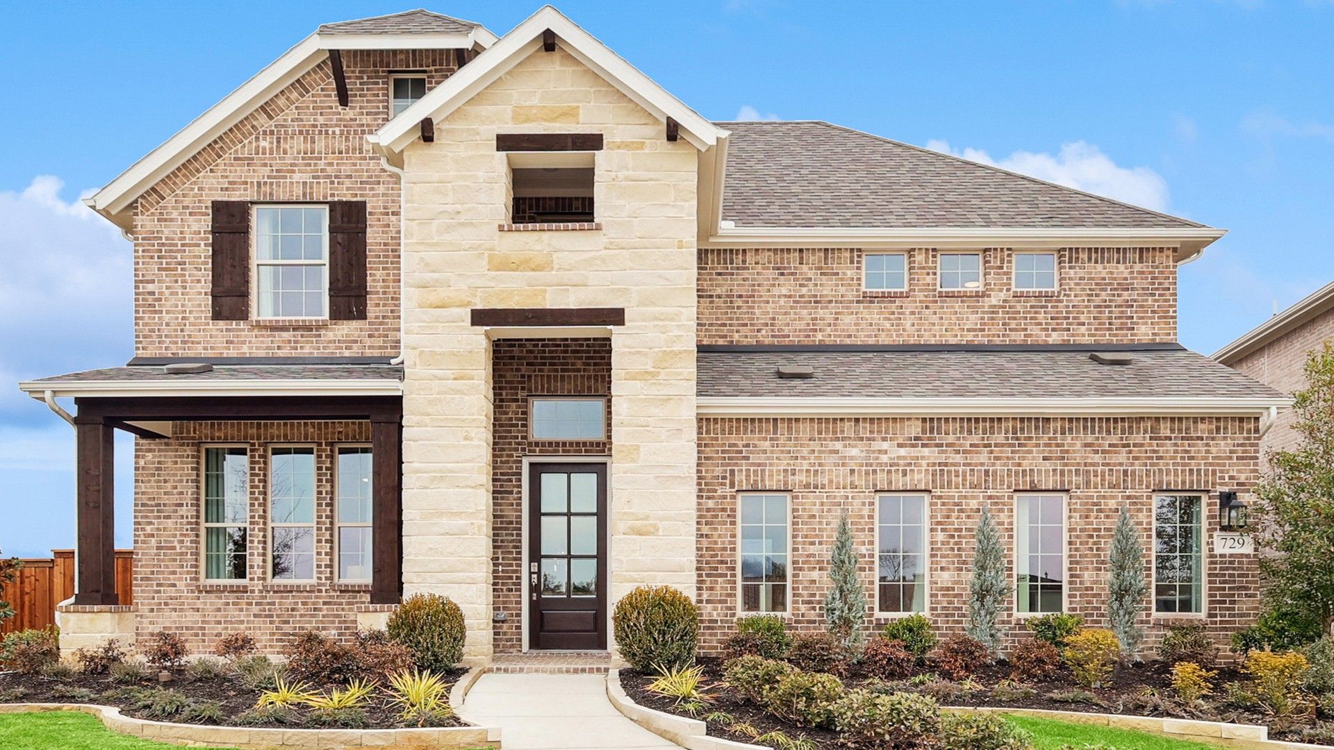 Luxurious brick facade with exquisite stone detailing in The Oaks. Pristine landscaping enhances this grand residence.