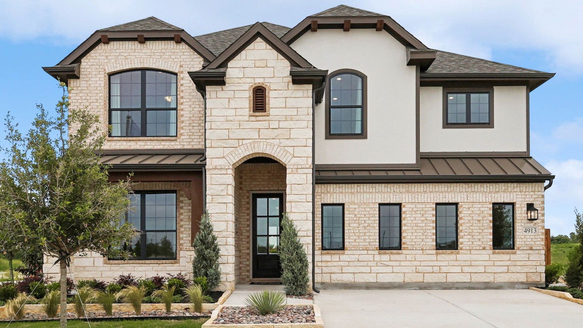 Elegant stone facade with arched entryway and expansive windows exemplifies luxury in Hulen Trails.