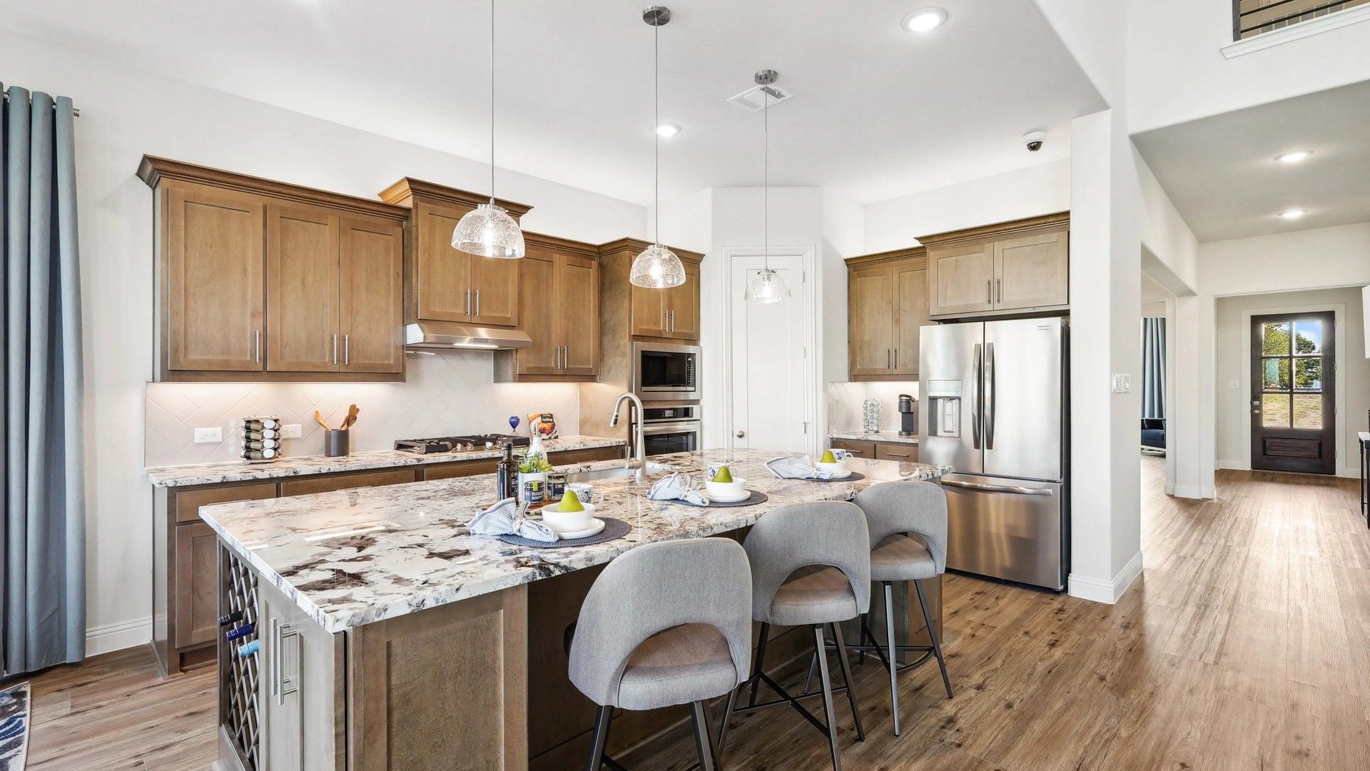 Ridge Crossing offers a sleek kitchen with marble island, stylish wood cabinetry, and elegant pendant lighting.