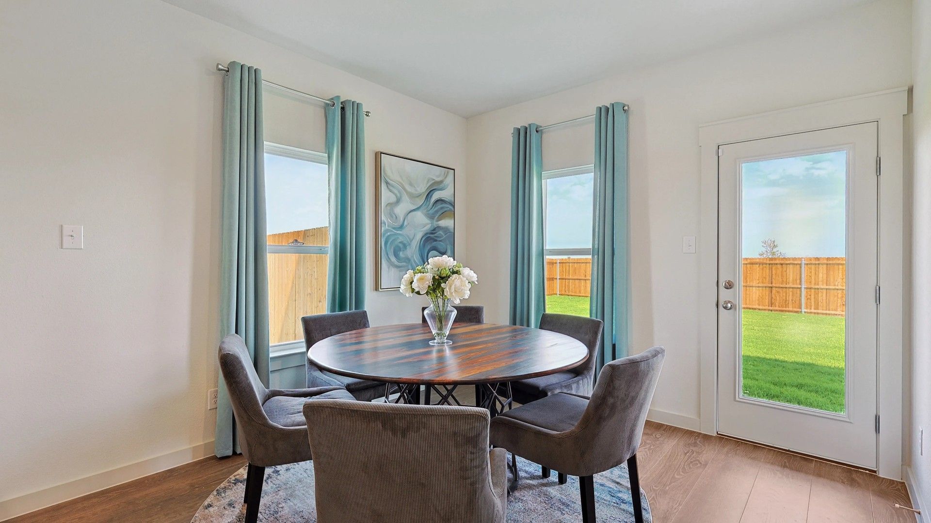 Experience elegance with a wooden table, plush chairs, and large windows in Patriot Estates.
