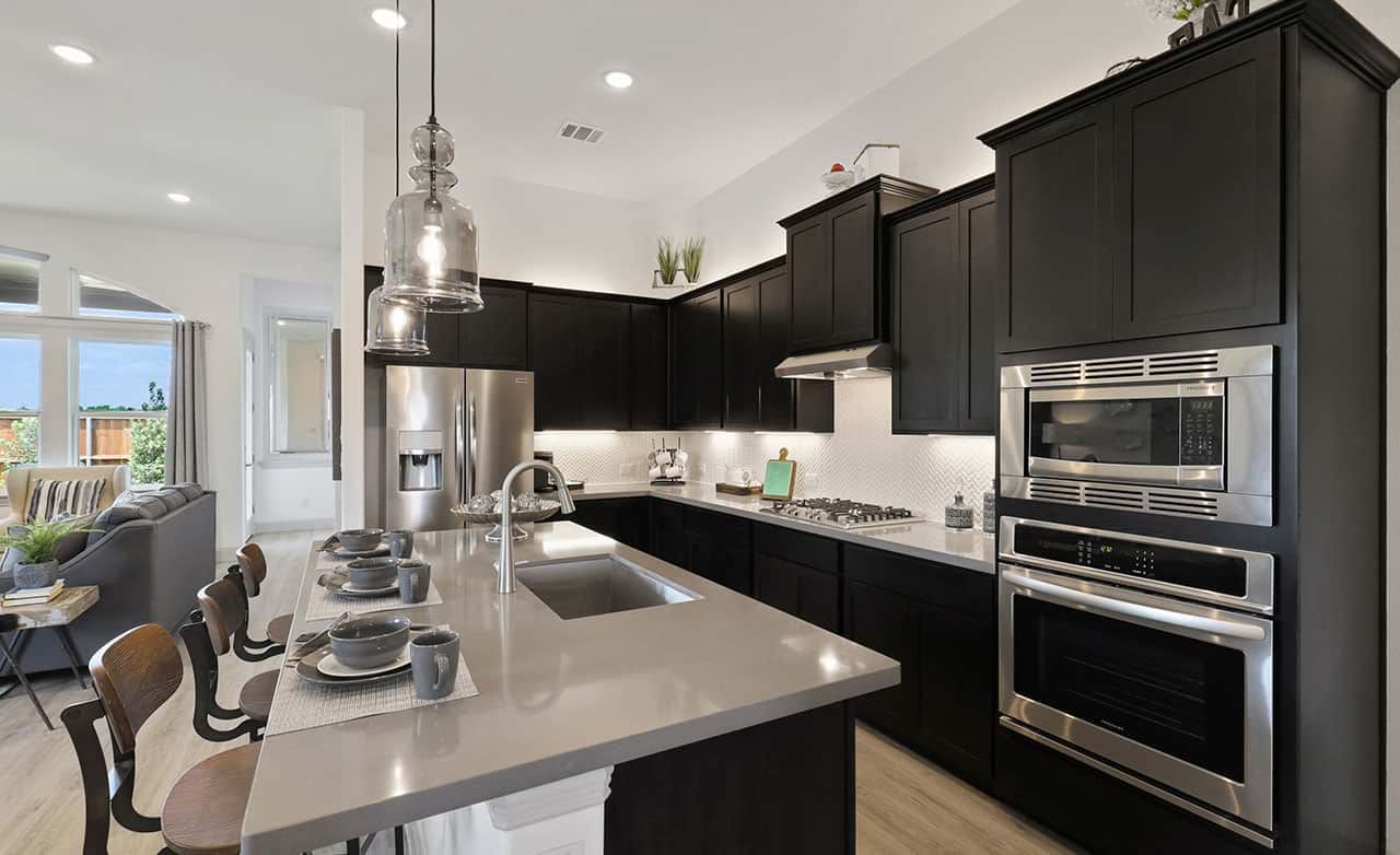 Experience luxury with sleek dark cabinetry and state-of-the-art appliances in Thompson Farms' elegant kitchen.