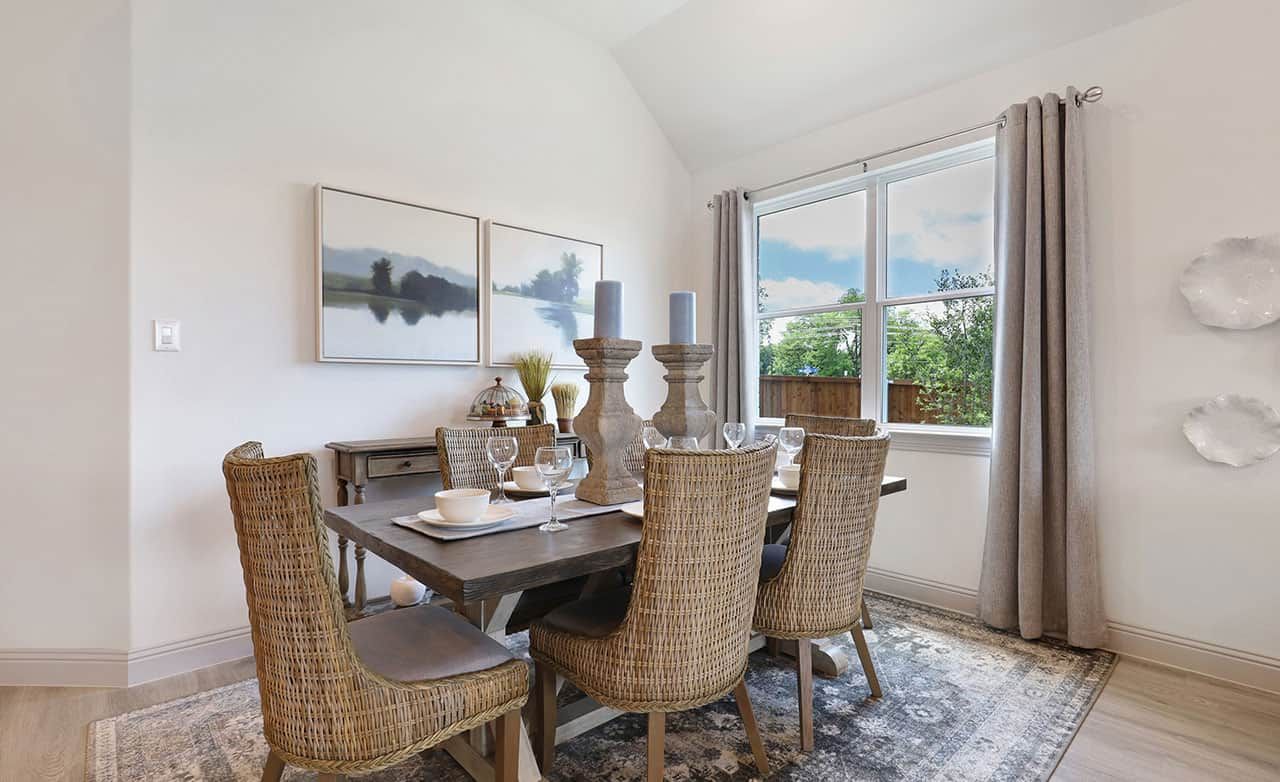 Experience refined rustic charm with woven seating, a wooden table, and expansive window views in Thompson Farms.