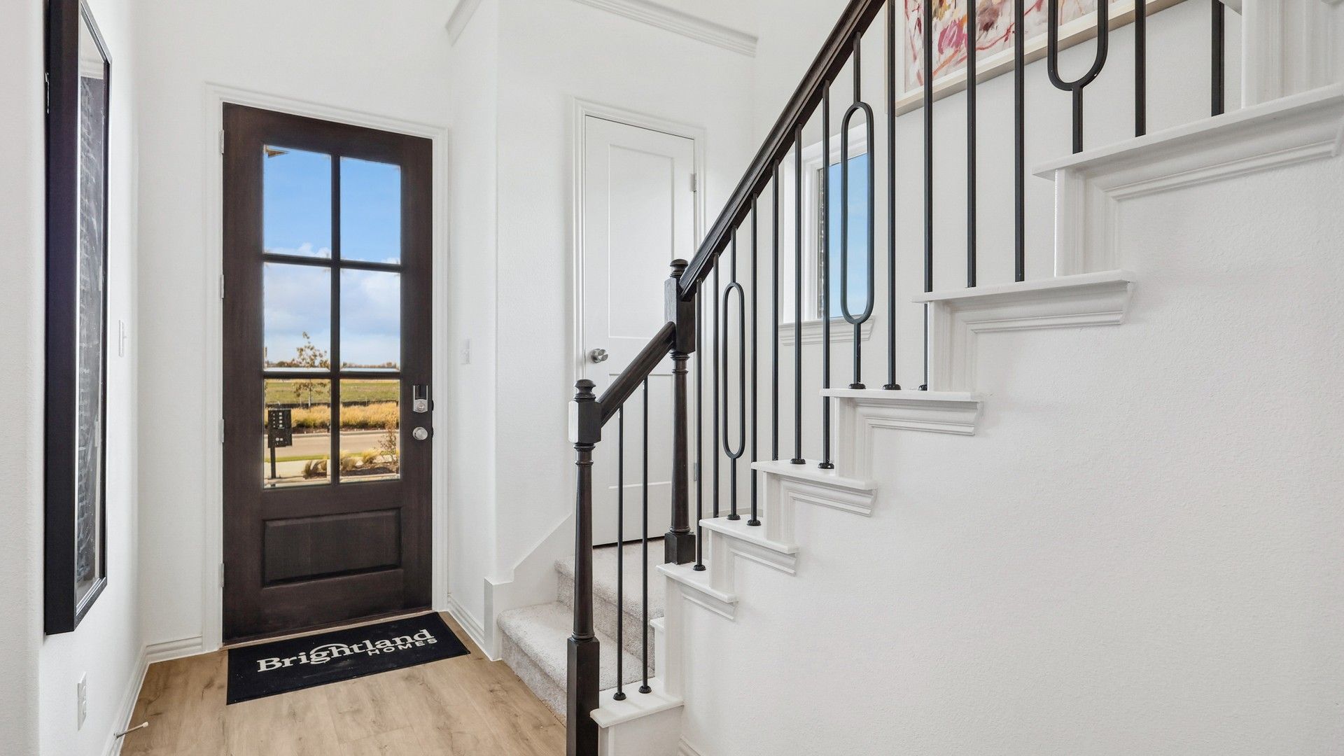 Bel Air Village foyer boasts refined wooden flooring and a chic black-framed glass door.