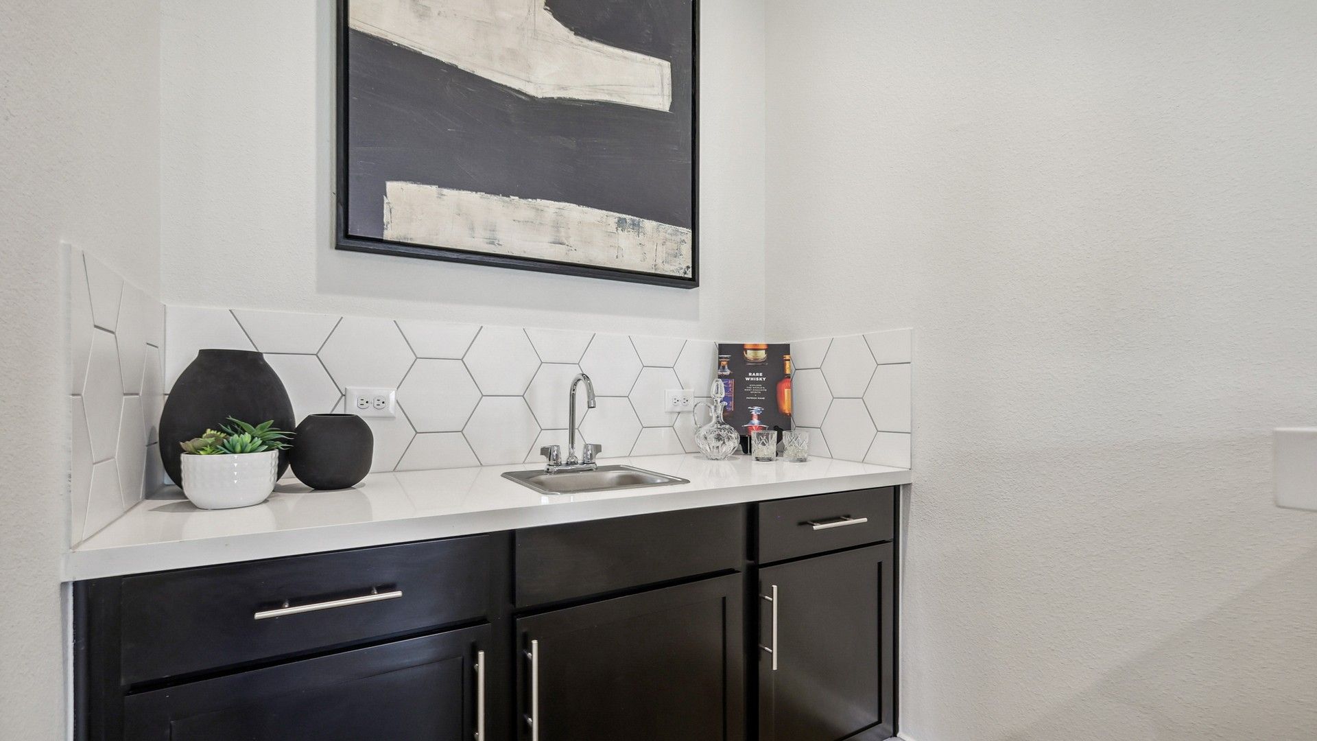 Elegant hexagonal backsplash and sleek black cabinetry define this Churchill wet bar.
