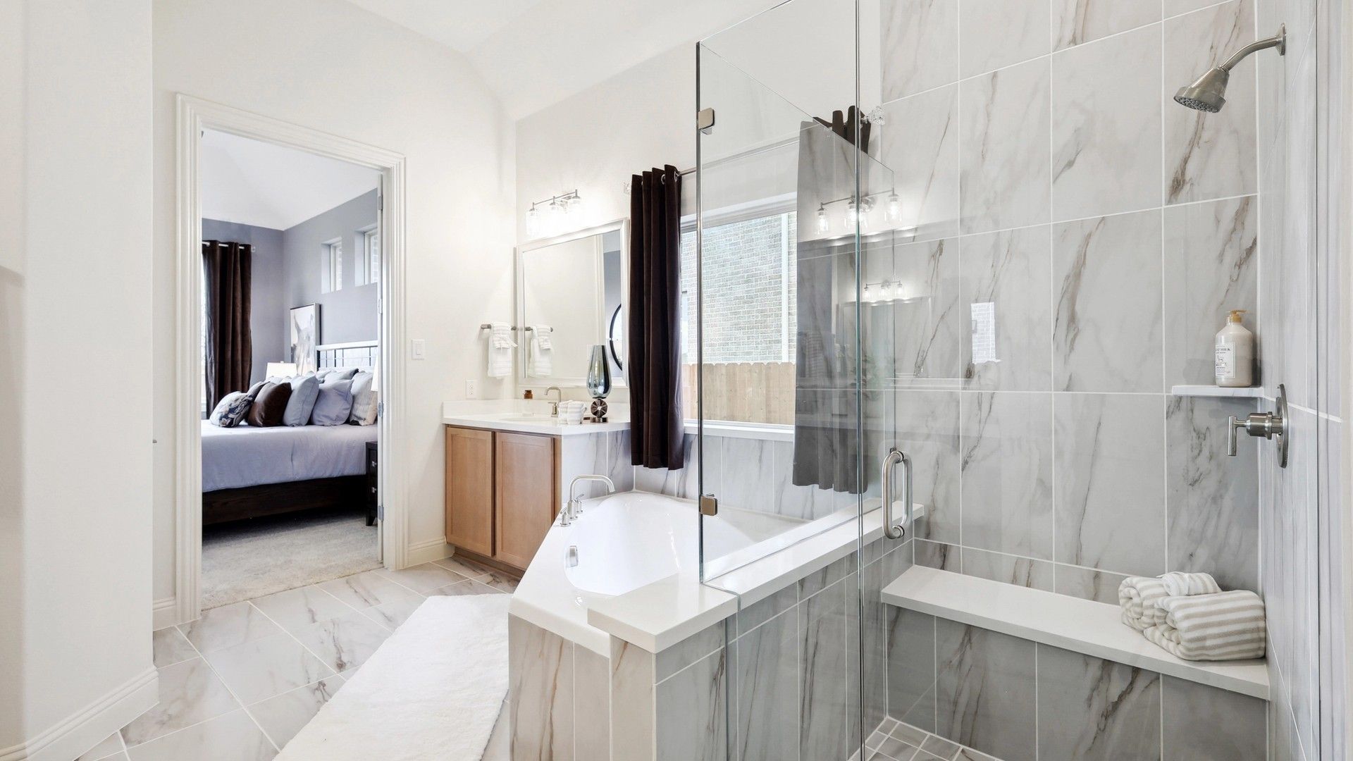 Indulge in this spa-like master bath with exquisite marble tiles and sleek glass shower in The Oaks.