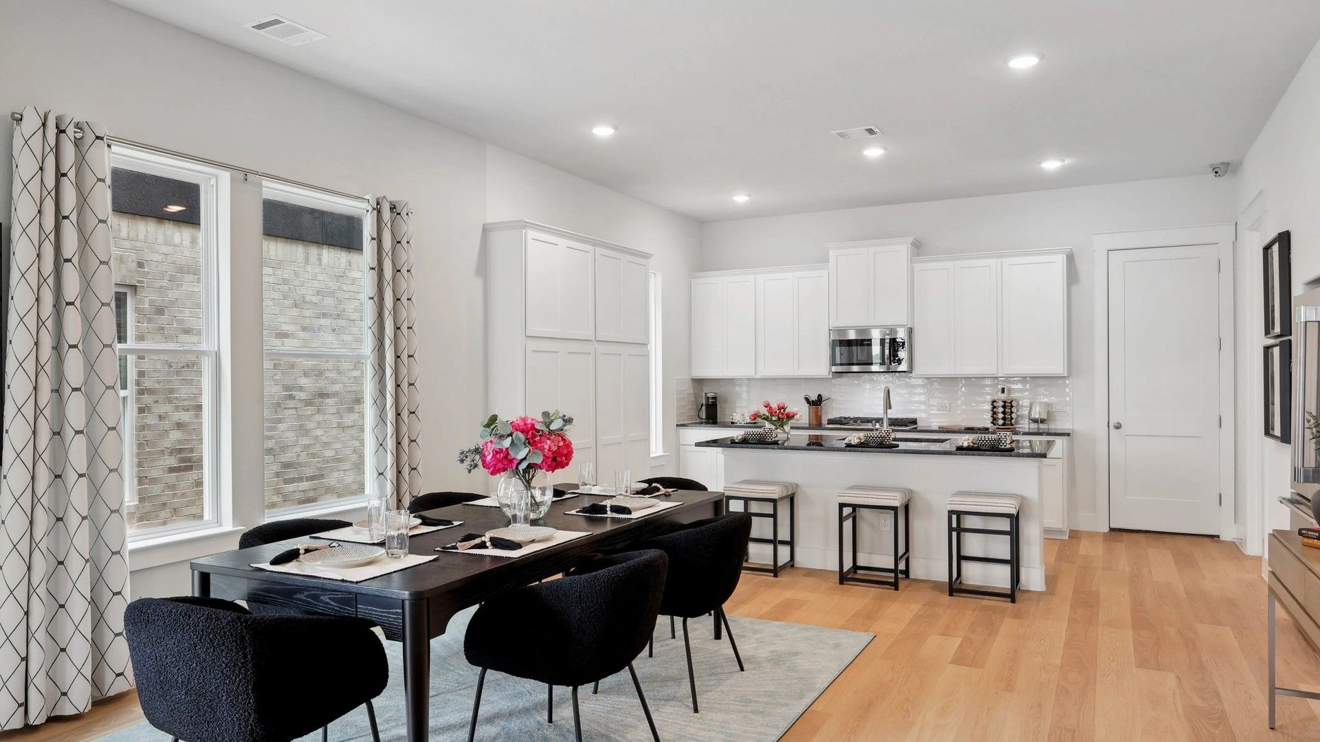 Luxurious Collin Creek kitchen with sleek white cabinetry and warm hardwood floors.